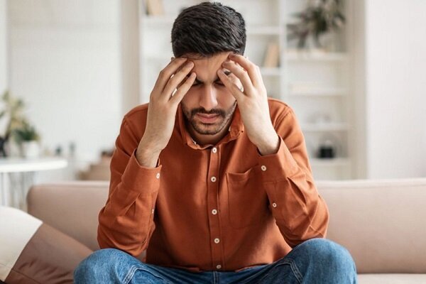 مرد نشسته ای که دستانش را روی سرش گرفته