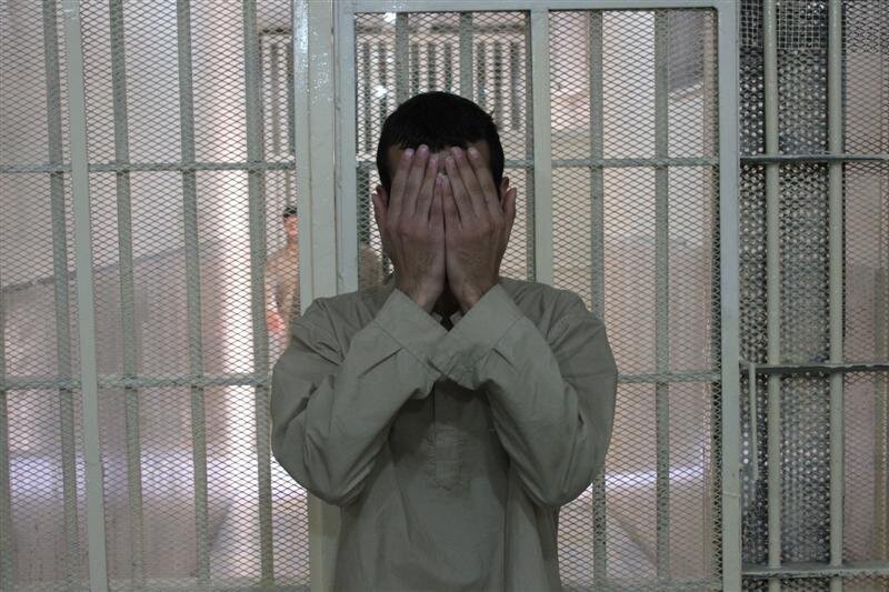 مردی در بازداشتگاه که صورت خود را با دو دست پوشانده مردی در بازداشتگاه که صورت خود را با دو دست پوشانده