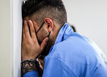 مجرمی که سرش رو به دیوار گذاشته و صورتش را پوشانده